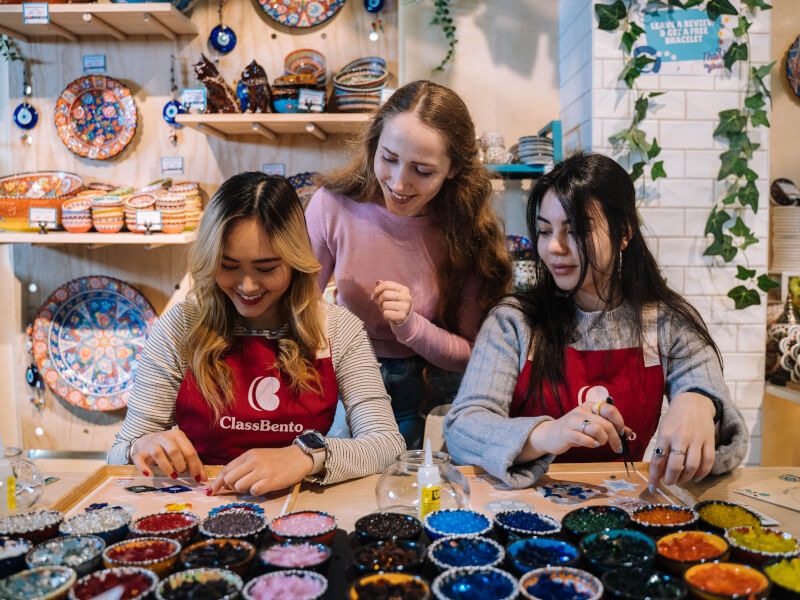 Two women making mosaics in a colourful room